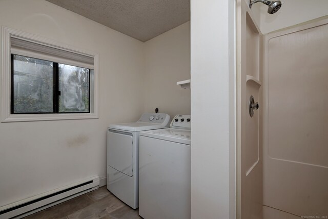 laundry area featuring baseboard heating, light hardwood / wood-style flooring, a textured ceiling, and washer and clothes dryer