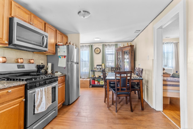 kitchen featuring appliances with stainless steel finishes, backsplash, light hardwood / wood-style floors, and a healthy amount of sunlight