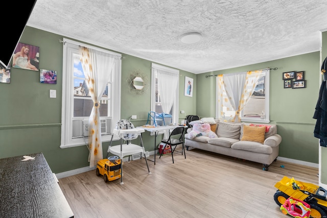 living room featuring cooling unit, light hardwood / wood-style flooring, and a textured ceiling