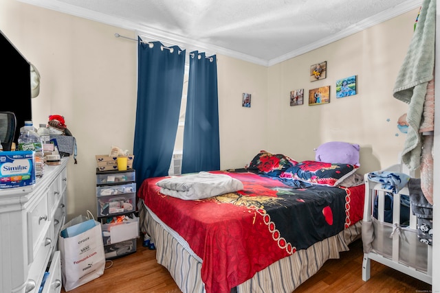 bedroom with a textured ceiling, light hardwood / wood-style flooring, and crown molding