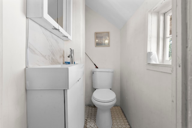 bathroom with lofted ceiling, tile patterned flooring, vanity, and toilet