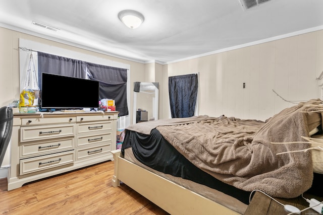 bedroom with wooden walls, light hardwood / wood-style flooring, and ornamental molding