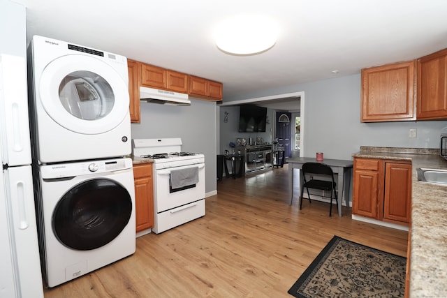 kitchen featuring stacked washer / drying machine, light wood-type flooring, sink, and gas range gas stove