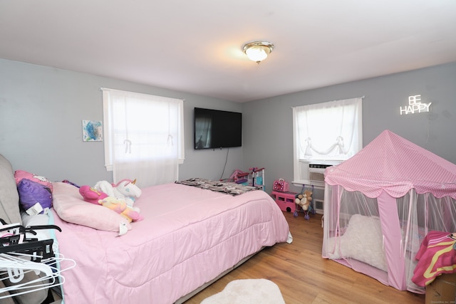 bedroom with cooling unit and light hardwood / wood-style floors