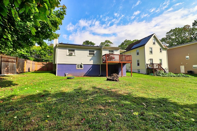 back of property with a wooden deck and a lawn