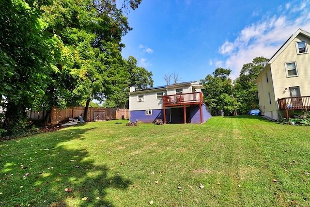 rear view of house with a lawn and a wooden deck