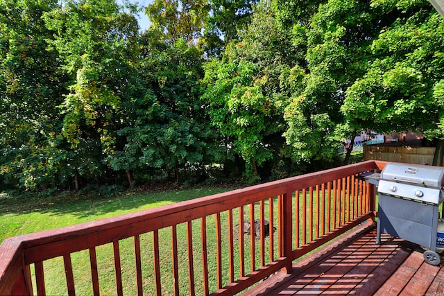 wooden deck with a yard and a grill