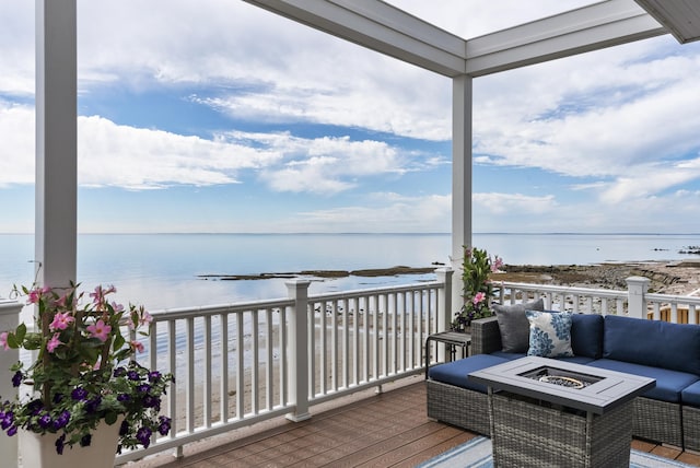 wooden deck with a water view and an outdoor living space with a fire pit