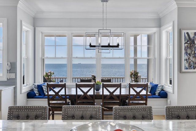 dining area with an inviting chandelier, a water view, a wealth of natural light, and crown molding