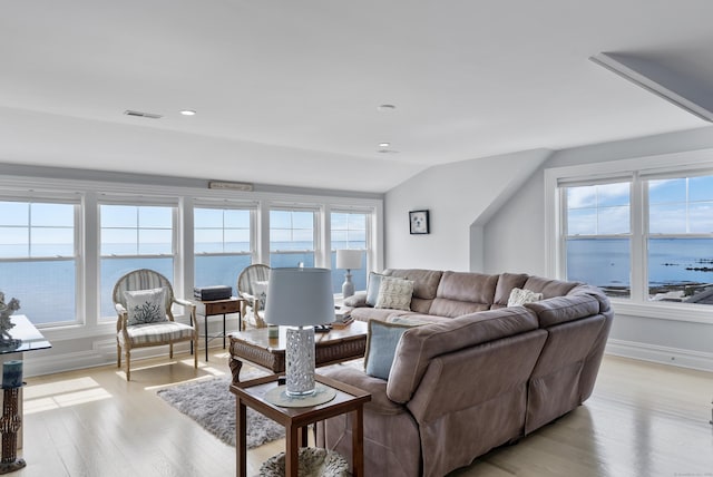 living room featuring visible vents, baseboards, lofted ceiling, a water view, and light wood-type flooring