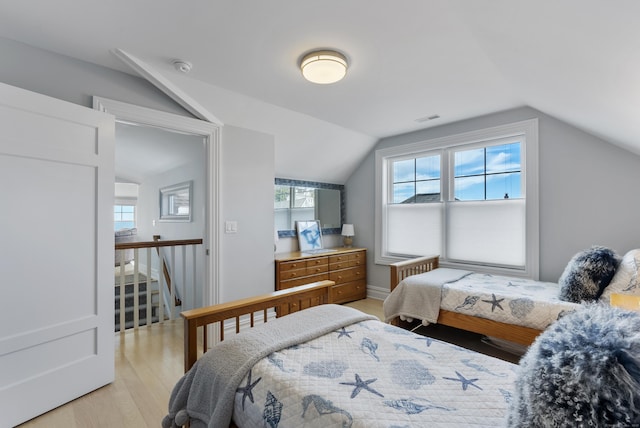 bedroom featuring lofted ceiling, light wood-style flooring, multiple windows, and visible vents