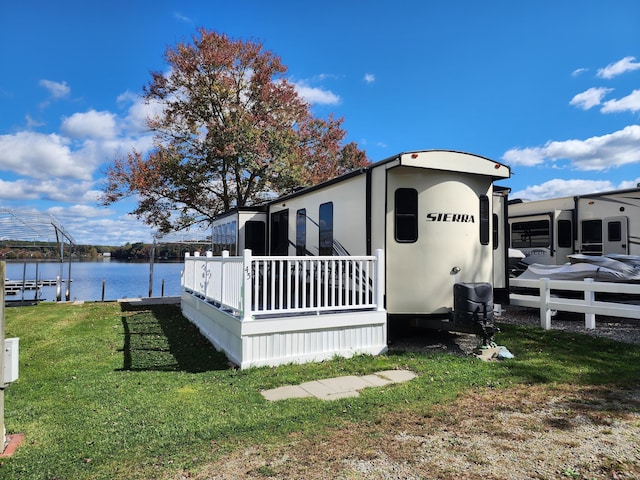 view of side of property with stucco siding, a water view, a yard, and a boat dock