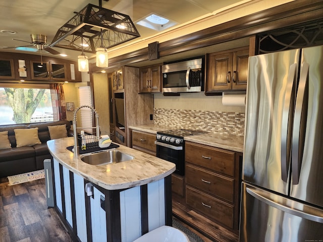 kitchen featuring an island with sink, light stone counters, dark hardwood / wood-style floors, stainless steel appliances, and sink