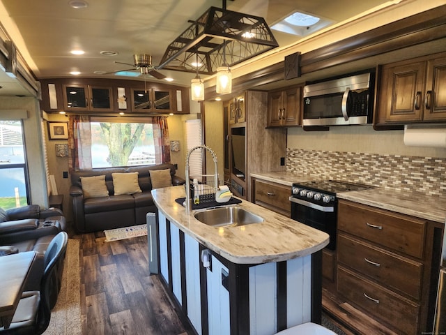 kitchen featuring light countertops, a sink, stainless steel microwave, electric range, and open floor plan