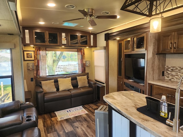 living area featuring a ceiling fan, visible vents, and dark wood-style floors