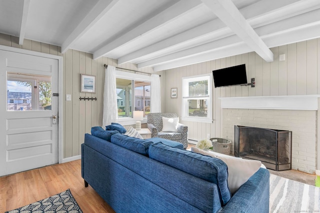 living room featuring wood walls, plenty of natural light, beam ceiling, and light wood-type flooring