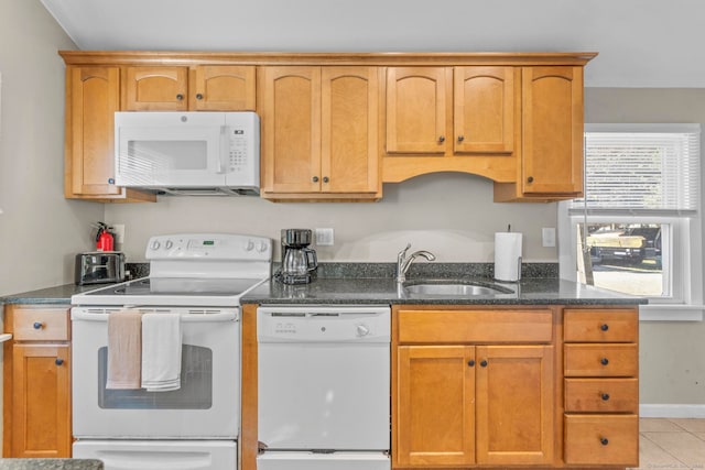 kitchen with dark stone counters, white appliances, sink, and light tile patterned floors