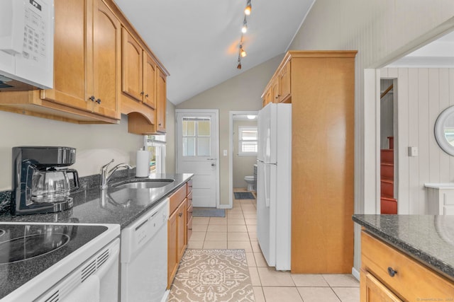 kitchen with lofted ceiling, white appliances, sink, dark stone counters, and light tile patterned floors