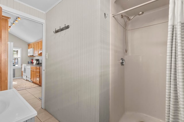 bathroom featuring vanity, lofted ceiling, tile patterned floors, walk in shower, and crown molding