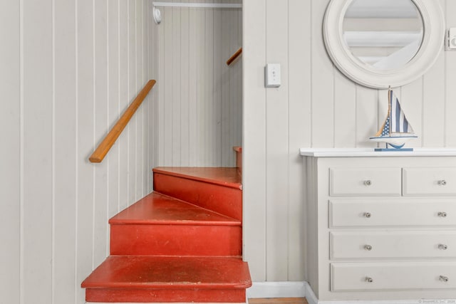 stairway featuring wooden walls