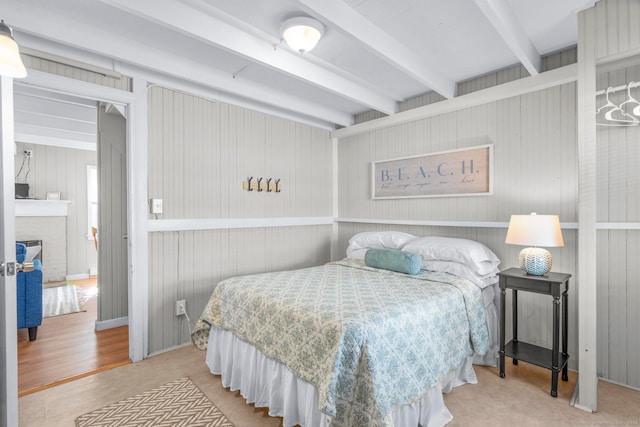 bedroom with wood walls, wood-type flooring, beam ceiling, and a fireplace