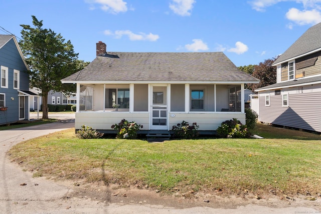 bungalow-style house featuring a sunroom and a front lawn