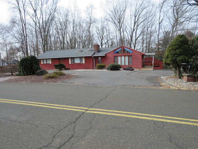 view of front facade with driveway and a chimney