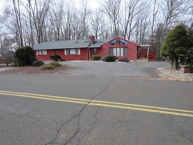 view of front facade featuring entry steps, driveway, and a chimney