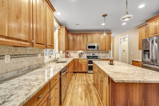 kitchen with appliances with stainless steel finishes, light stone counters, sink, decorative light fixtures, and light hardwood / wood-style floors