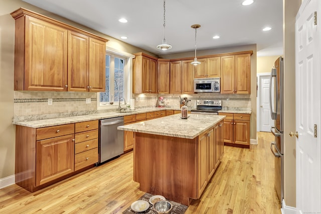 kitchen featuring a center island, backsplash, light hardwood / wood-style flooring, appliances with stainless steel finishes, and decorative light fixtures