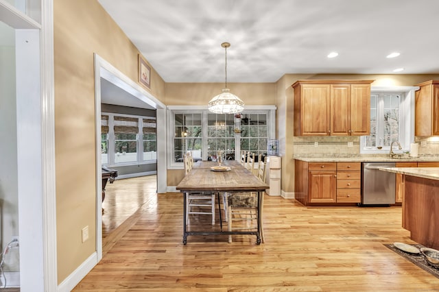 kitchen featuring sink, dishwasher, hanging light fixtures, decorative backsplash, and light wood-type flooring