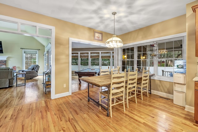 dining space featuring light hardwood / wood-style floors, a brick fireplace, lofted ceiling, and pool table