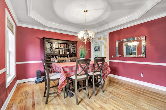 dining area with a tray ceiling, hardwood / wood-style flooring, crown molding, and an inviting chandelier