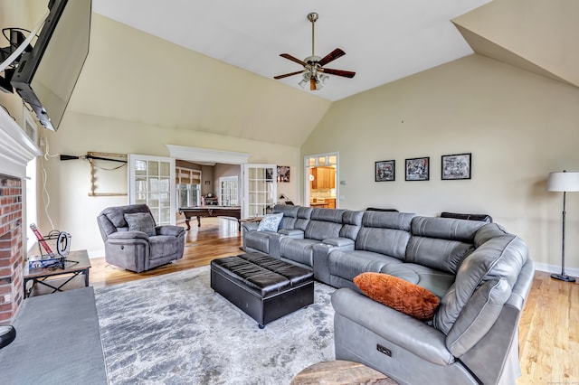 living room featuring ceiling fan, high vaulted ceiling, billiards, a fireplace, and light wood-type flooring