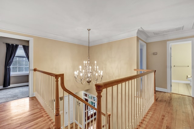 hall featuring light wood-type flooring, crown molding, and a notable chandelier