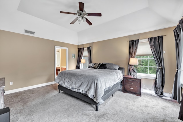 carpeted bedroom with a tray ceiling, ceiling fan, and ensuite bathroom