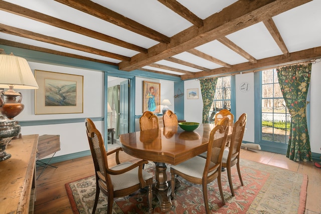 dining space with light wood-type flooring and beam ceiling