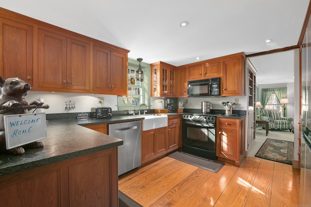 kitchen with black appliances, pendant lighting, sink, and light hardwood / wood-style flooring