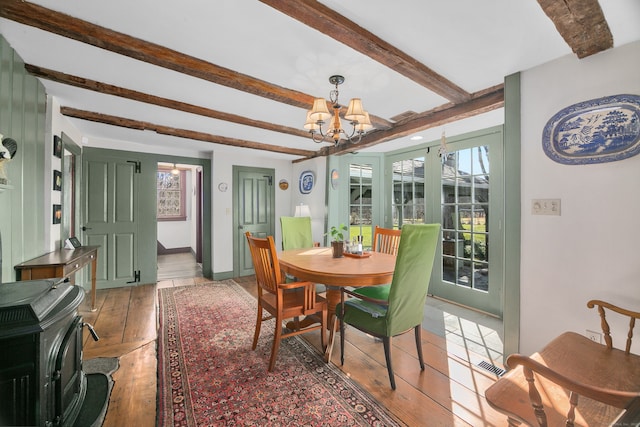 dining space with a notable chandelier, beamed ceiling, and hardwood / wood-style flooring