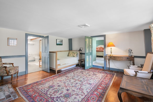 bedroom featuring connected bathroom and dark wood-type flooring