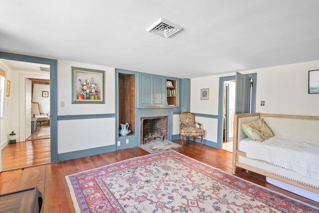 bedroom featuring a brick fireplace and hardwood / wood-style flooring