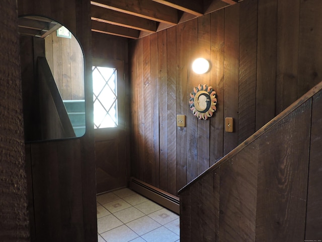 doorway to outside with light tile patterned flooring, a baseboard radiator, and wooden walls