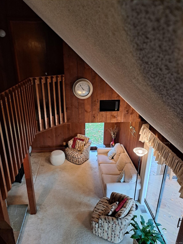 interior space featuring vaulted ceiling, carpet flooring, and wooden walls