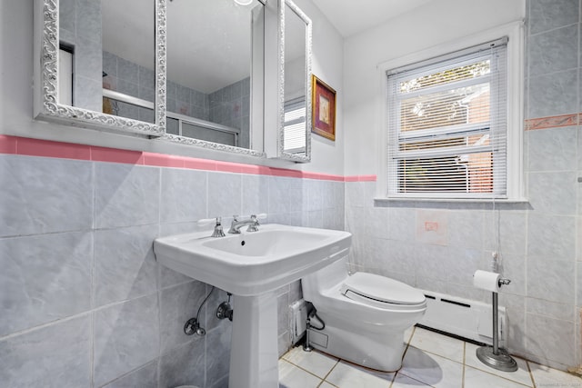 bathroom featuring a baseboard radiator, tile patterned floors, toilet, and tile walls