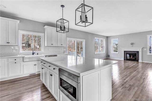 kitchen with a kitchen island, a wealth of natural light, white cabinetry, and decorative light fixtures