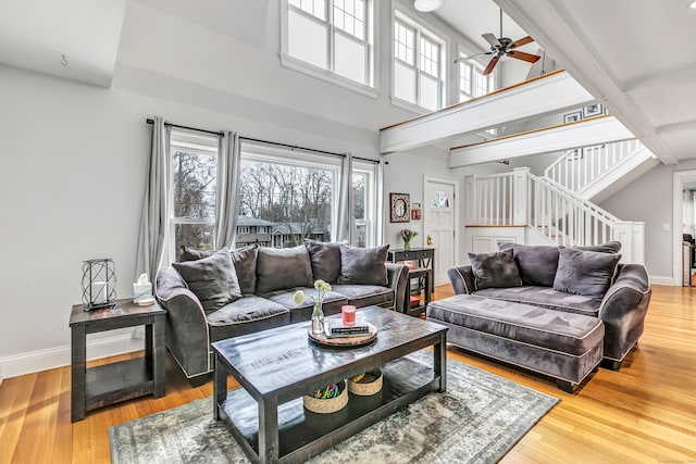 living room with wood-type flooring, ceiling fan, and beamed ceiling