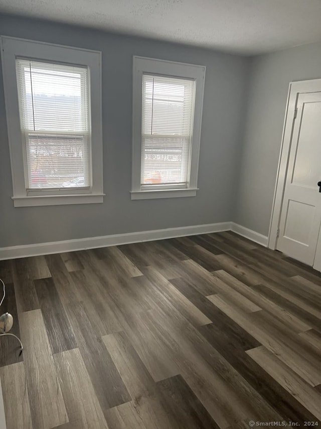 unfurnished room featuring a textured ceiling and dark hardwood / wood-style flooring