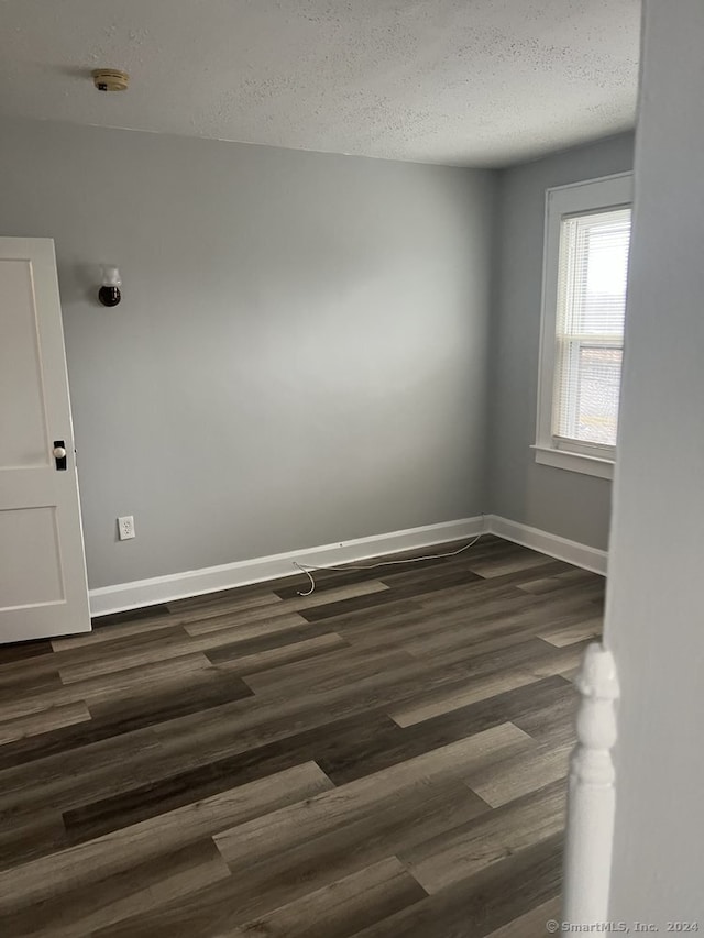 empty room with a textured ceiling and dark wood-type flooring