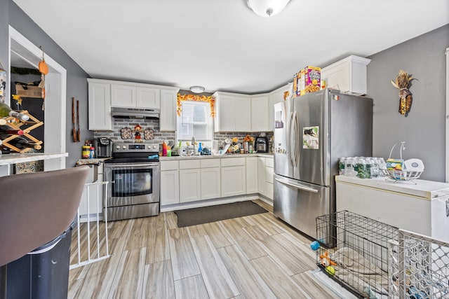 kitchen with white cabinetry, backsplash, stainless steel appliances, light wood-type flooring, and sink