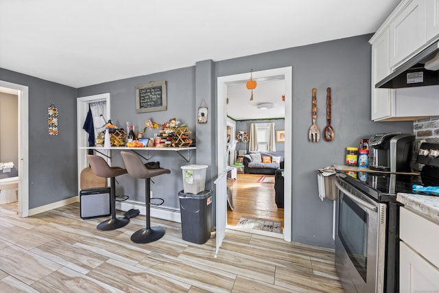 kitchen featuring wall chimney exhaust hood, white cabinetry, electric range, a baseboard radiator, and light hardwood / wood-style floors